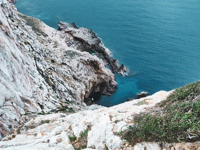 白天蓝海边灰色的岩石山